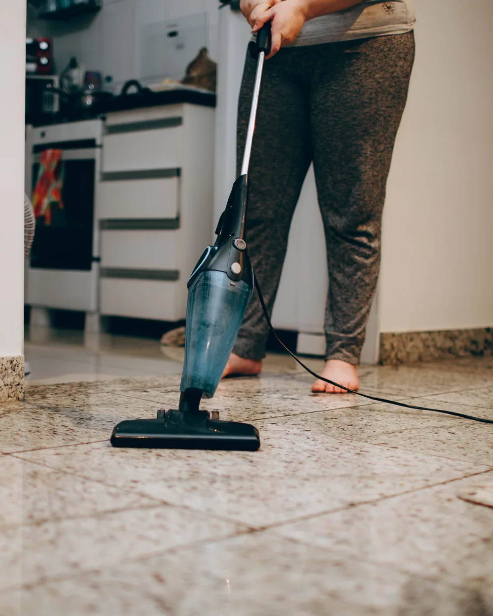 Person cleaning a residential floor while a dog stands nearby