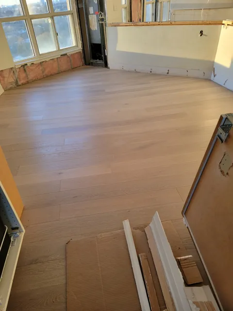 New engineered hardwood across the open living area by the windows, Toronto condo after water damage