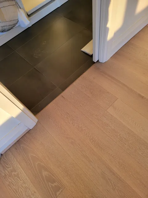 New engineered hardwood meeting dark floor tile at a doorway