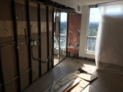 Room with walls opened to the studs and old flooring pulled up after the leak, Toronto condo