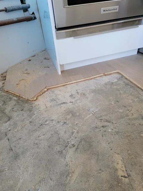 Old floor removed and subfloor scraped right up to the existing kitchen cabinets and range