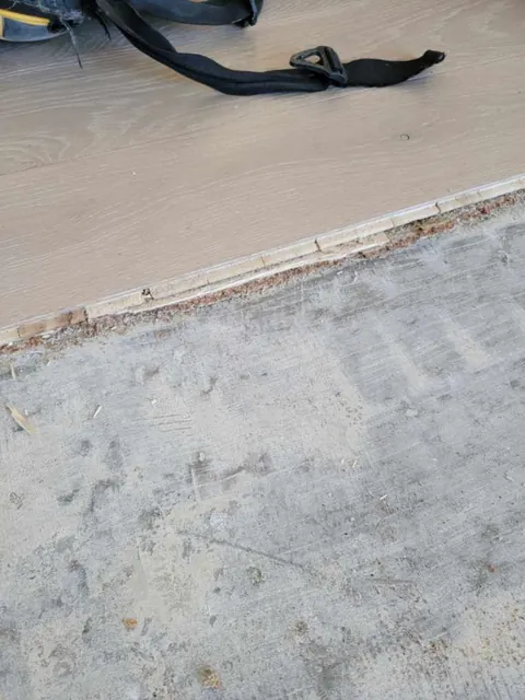 Removal in progress, with the old glued-down floor above and the scraped subfloor below